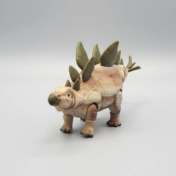 A small articulated toy Stegosaurus figurine with a textured beige and brown body, green spikes, and a dark green snout, standing on a light gray gradient background.